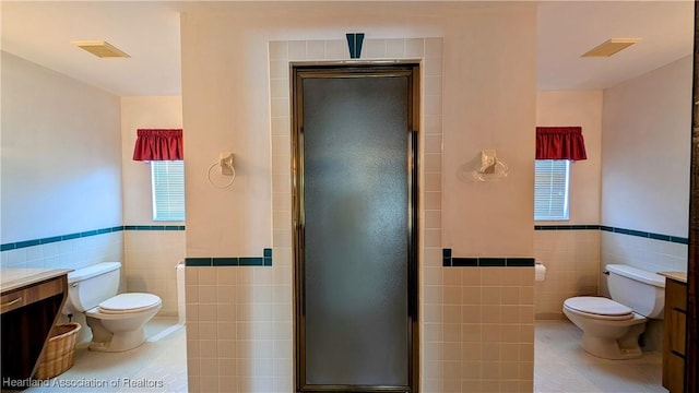 bathroom with tile walls, toilet, tile patterned floors, a wainscoted wall, and vanity