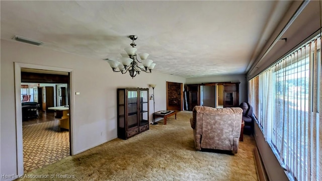 living area with healthy amount of natural light, a chandelier, carpet floors, and baseboards