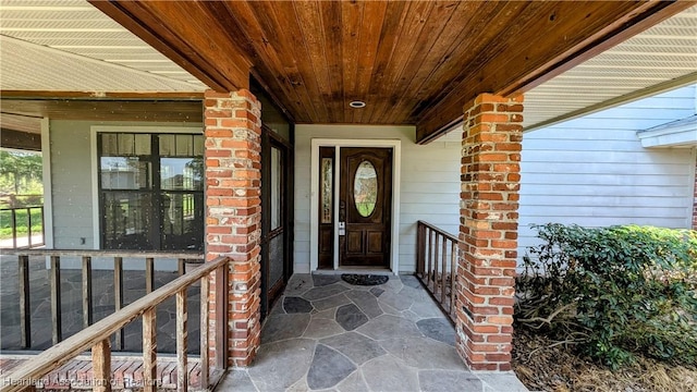 doorway to property featuring a porch and brick siding
