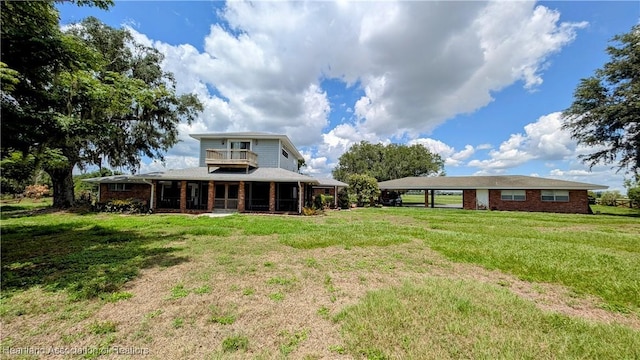 back of house featuring brick siding, a yard, and a carport