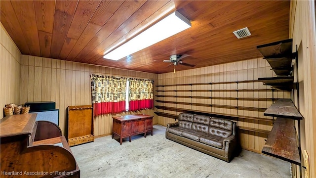 sitting room with ceiling fan, wooden ceiling, wood walls, and carpet flooring