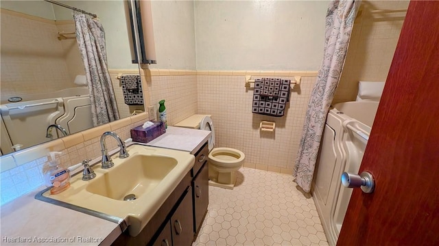 bathroom featuring tile walls, shower / bath combo, wainscoting, vanity, and toilet