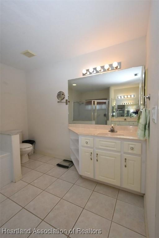 bathroom with tile patterned floors, vanity, toilet, and walk in shower