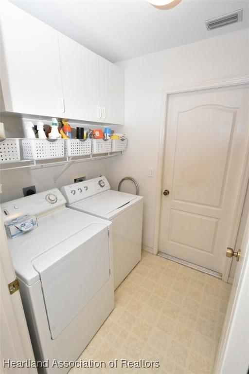 laundry room with washing machine and dryer and cabinets