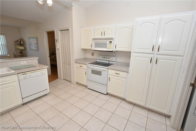 kitchen featuring white cabinets, lofted ceiling, white appliances, and light tile patterned floors