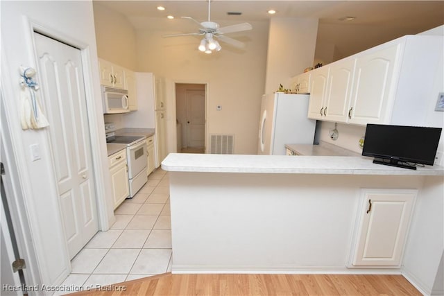 kitchen with white appliances, kitchen peninsula, ceiling fan, light tile patterned flooring, and white cabinetry