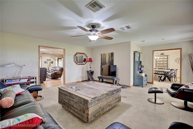 living area featuring ceiling fan, visible vents, and baseboards