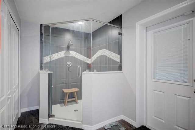 full bath featuring a shower stall and baseboards