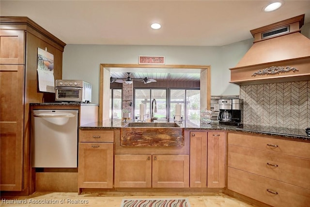 kitchen with a sink, black electric cooktop, dark stone counters, and backsplash