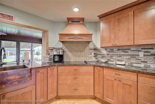 kitchen with dark stone counters, black electric stovetop, premium range hood, and tasteful backsplash