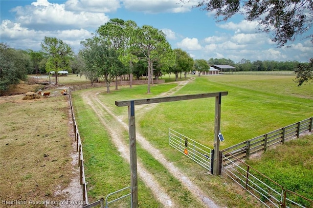 view of property's community featuring dirt driveway, a rural view, and fence