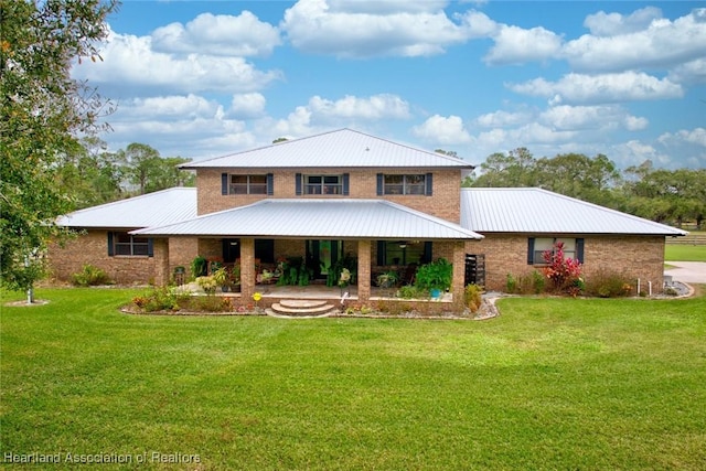 rear view of property with brick siding, metal roof, and a yard