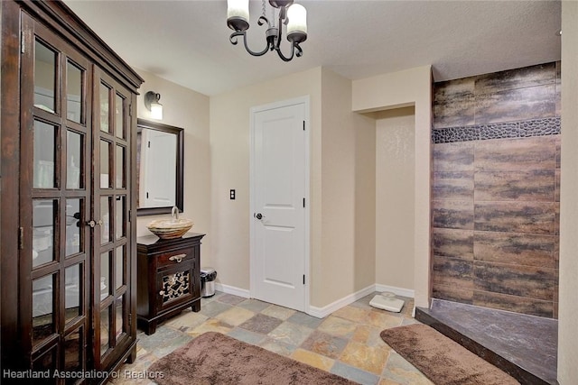 entrance foyer with a chandelier, stone finish floor, and baseboards