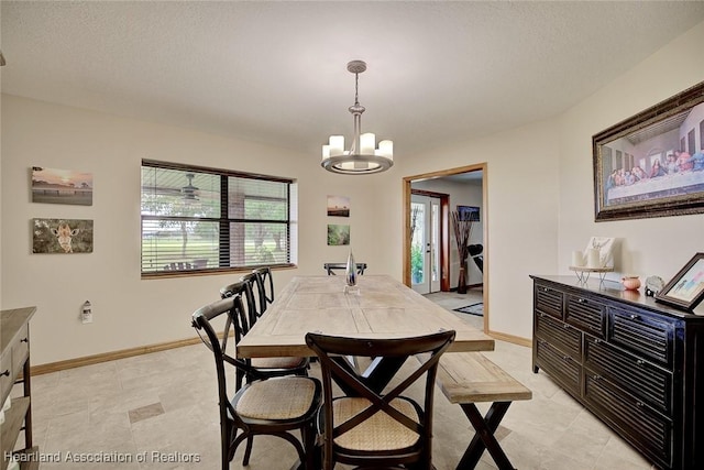 dining space with a textured ceiling, baseboards, and an inviting chandelier