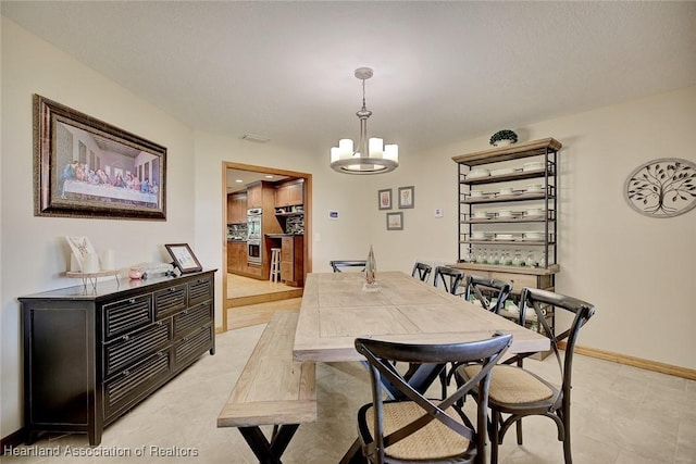 dining room featuring an inviting chandelier and baseboards