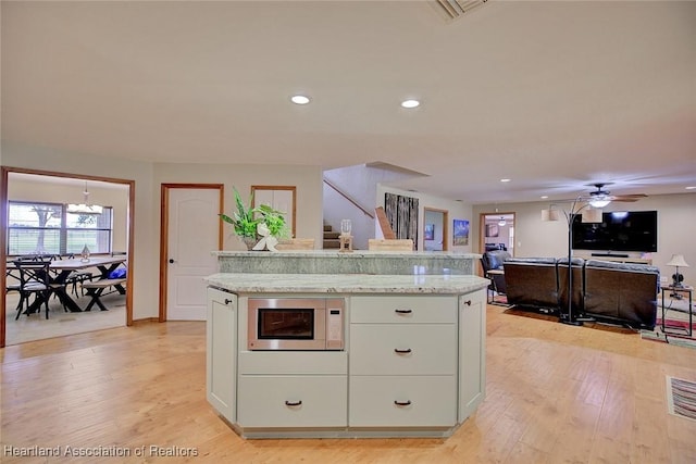 kitchen with white cabinetry, light wood-style flooring, built in microwave, and recessed lighting