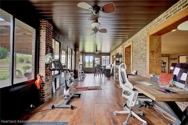 exercise room featuring brick wall, ceiling fan, and tile patterned floors