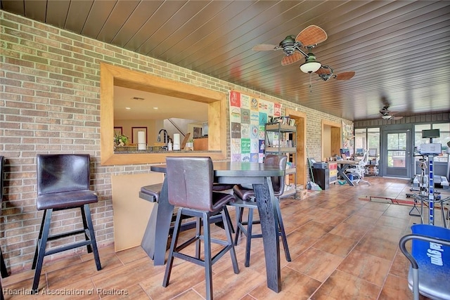 interior space featuring brick wall, wooden ceiling, and a ceiling fan