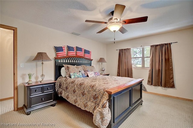 bedroom featuring light carpet, ceiling fan, a textured ceiling, and baseboards