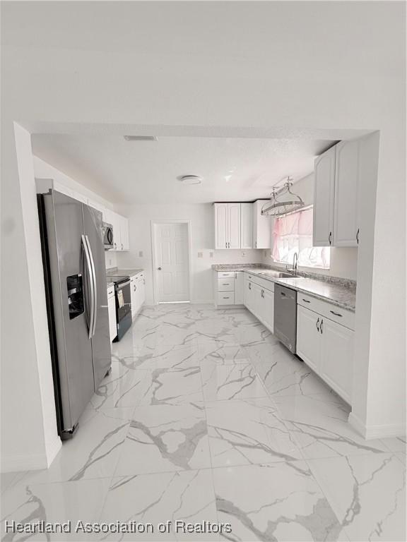 kitchen featuring marble finish floor, light countertops, appliances with stainless steel finishes, and white cabinets