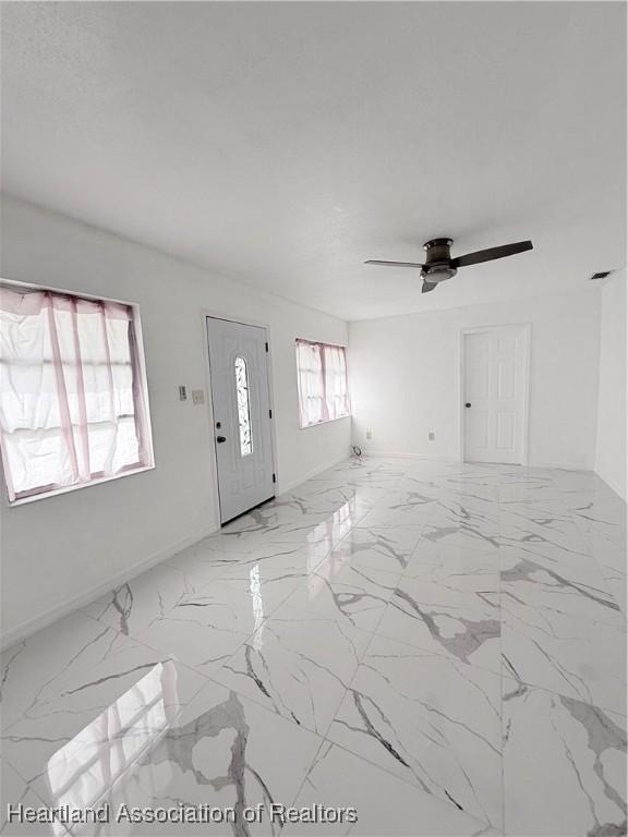 unfurnished living room featuring marble finish floor, visible vents, and a ceiling fan