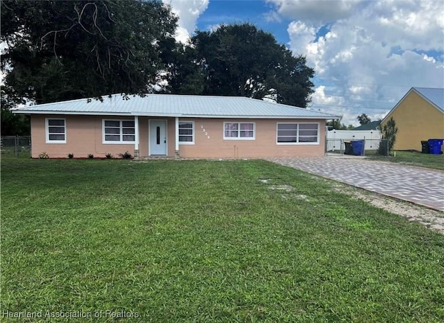 ranch-style home with fence, metal roof, and a front yard