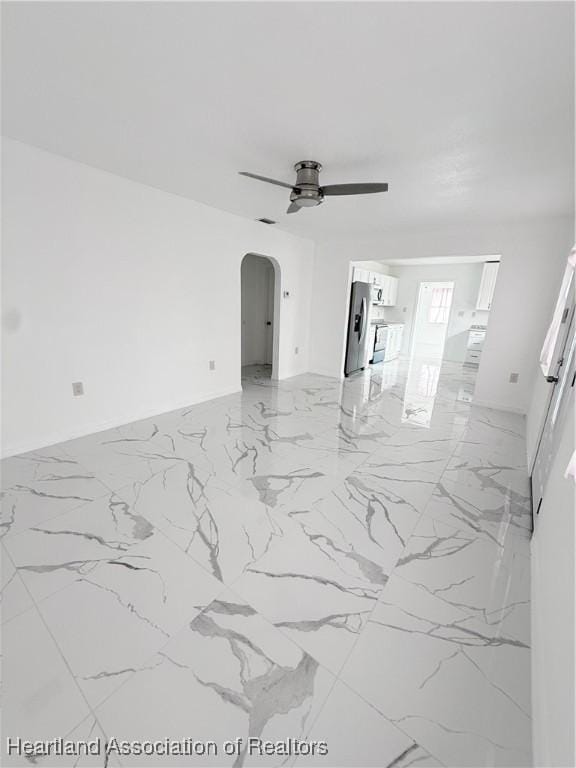 unfurnished living room featuring arched walkways, marble finish floor, and ceiling fan