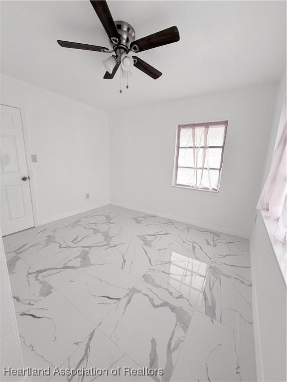 unfurnished room with marble finish floor and baseboards