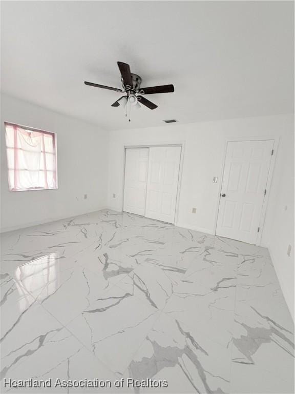 interior space with marble finish floor, visible vents, a ceiling fan, and a closet