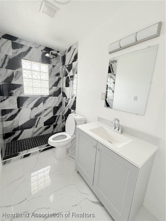 bathroom featuring marble finish floor, visible vents, toilet, vanity, and a shower stall