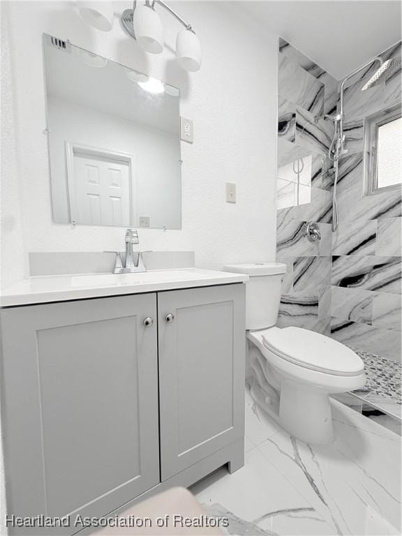 full bathroom with toilet, marble finish floor, a marble finish shower, and vanity