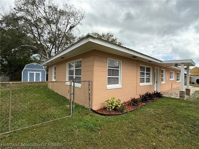 view of property exterior featuring a storage shed, a lawn, a patio, fence, and an outdoor structure