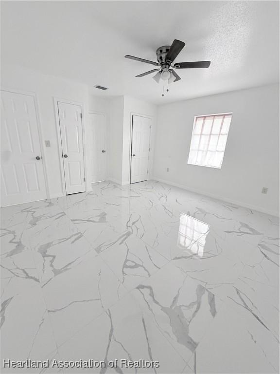 spare room featuring marble finish floor, baseboards, visible vents, and a textured ceiling