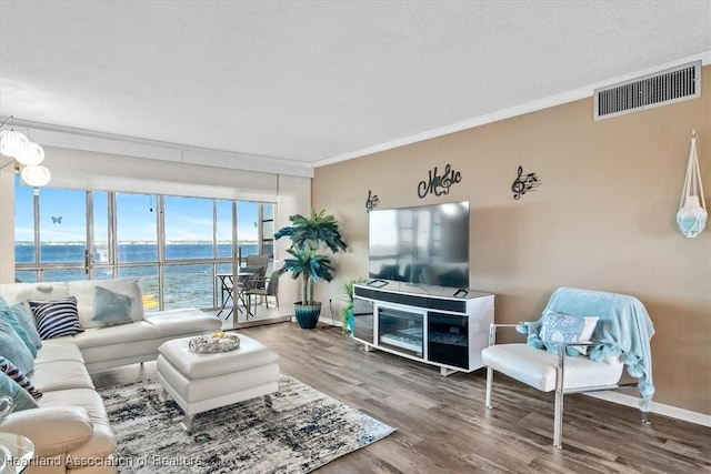 living area featuring visible vents, crown molding, baseboards, and wood finished floors