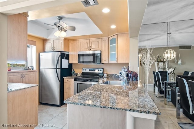 kitchen with stone countertops, visible vents, appliances with stainless steel finishes, light brown cabinets, and a sink