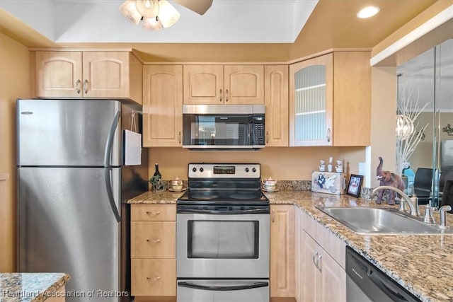 kitchen featuring a sink, stainless steel appliances, light stone counters, and light brown cabinets