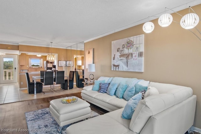 living area featuring an inviting chandelier, crown molding, a textured ceiling, and wood finished floors