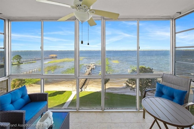 sunroom featuring a water view and a ceiling fan