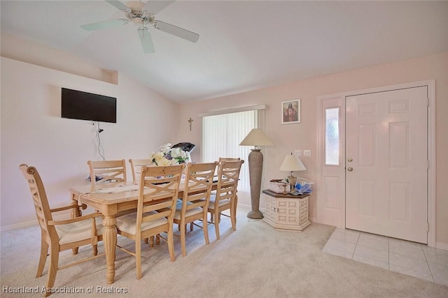 carpeted dining room featuring vaulted ceiling, tile patterned flooring, and a ceiling fan