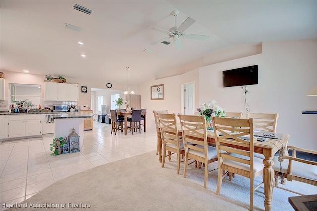 dining room with light carpet, light tile patterned flooring, lofted ceiling, and visible vents