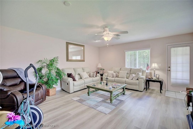 living area featuring ceiling fan, light wood-style flooring, and baseboards