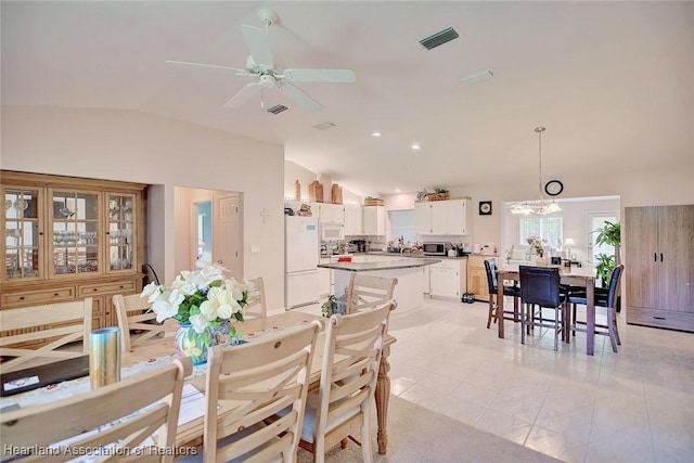 dining space with lofted ceiling, light tile patterned flooring, ceiling fan with notable chandelier, and visible vents