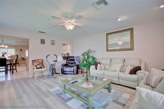 living room featuring light wood-style flooring, visible vents, ceiling fan, and baseboards