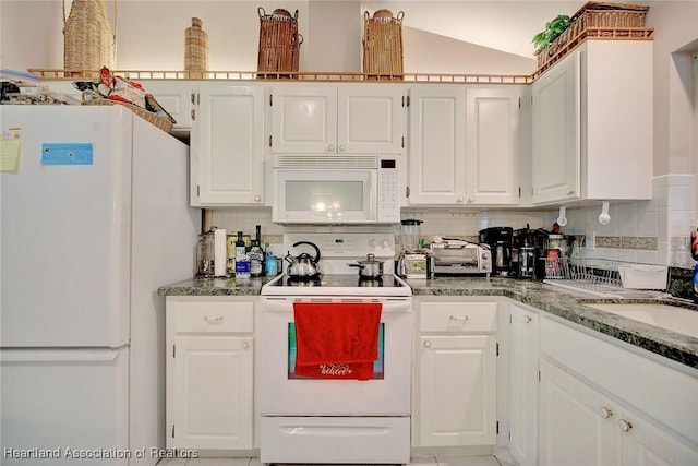 kitchen featuring lofted ceiling, backsplash, white cabinets, a sink, and white appliances