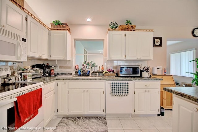 kitchen with white appliances, a sink, white cabinets, and decorative backsplash