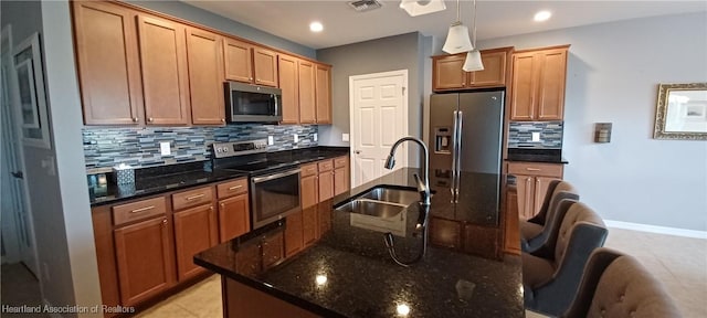 kitchen with dark stone counters, sink, hanging light fixtures, and appliances with stainless steel finishes