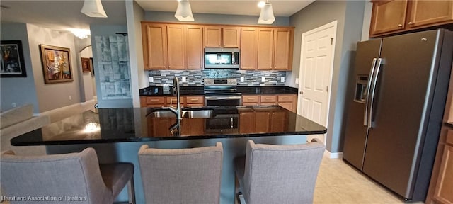 kitchen featuring appliances with stainless steel finishes, a center island with sink, a kitchen breakfast bar, and sink