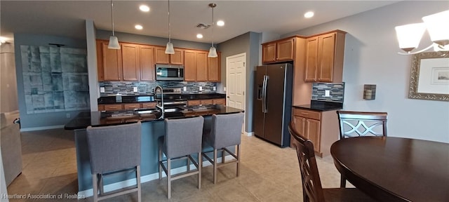 kitchen with decorative backsplash, hanging light fixtures, appliances with stainless steel finishes, and an inviting chandelier