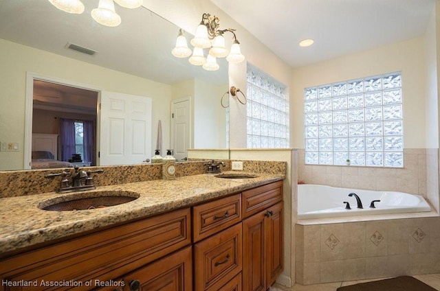 bathroom with tiled bath, tile patterned flooring, and vanity