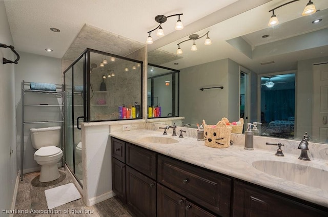 bathroom featuring vanity, ceiling fan, hardwood / wood-style floors, toilet, and a shower with shower door